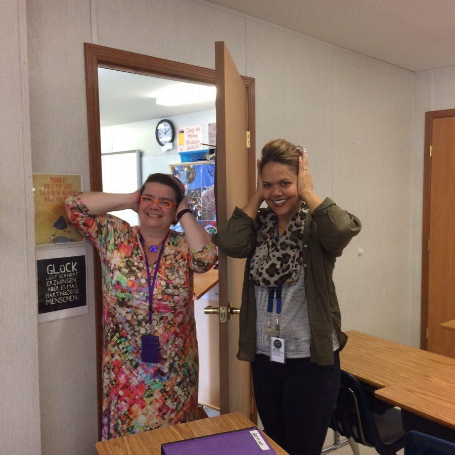 Teacjers Janine Williams and Katharina Fuerst pose for a photo to show how their students must cover their ears in Sparta, to improve their focus. 