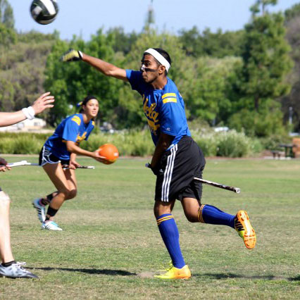 The UCLA Ouidditch team player passing the quaffle to another teammate hoping to score a goal to win the match.
