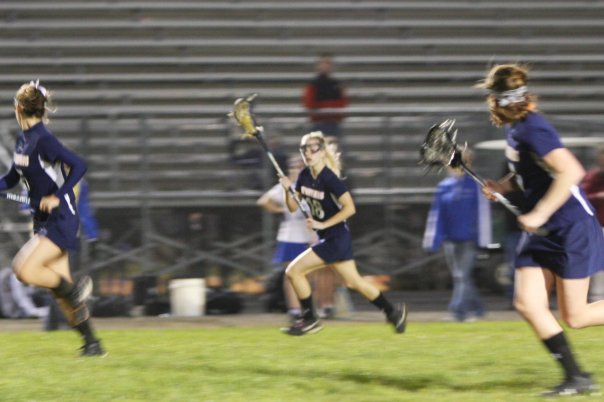 Katie Tinsley, number 18, cradles the lacrosse ball in her stick as she runs it down the field, back when she played on the WS girls lacrosse team. Tinsley now coaches the JV girls team along with Alexa Romano.