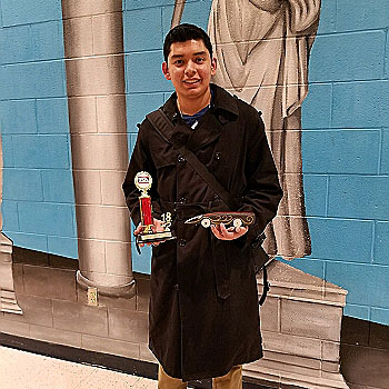 Senior Walter Ferrufino poses with his trophy, and his winning dragster, after securing first place at he regional TSA competition.