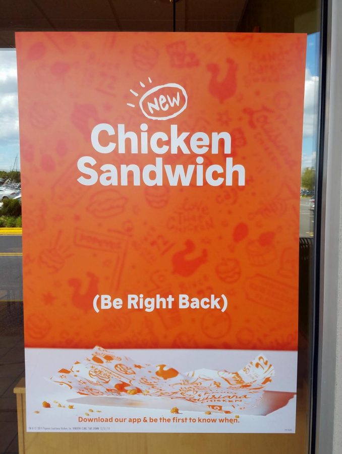 A poster on the outside of a Popeyes restaurant informs unsuspecting customers of the lack of sandwiches. The common message sends many disappointed customers away.