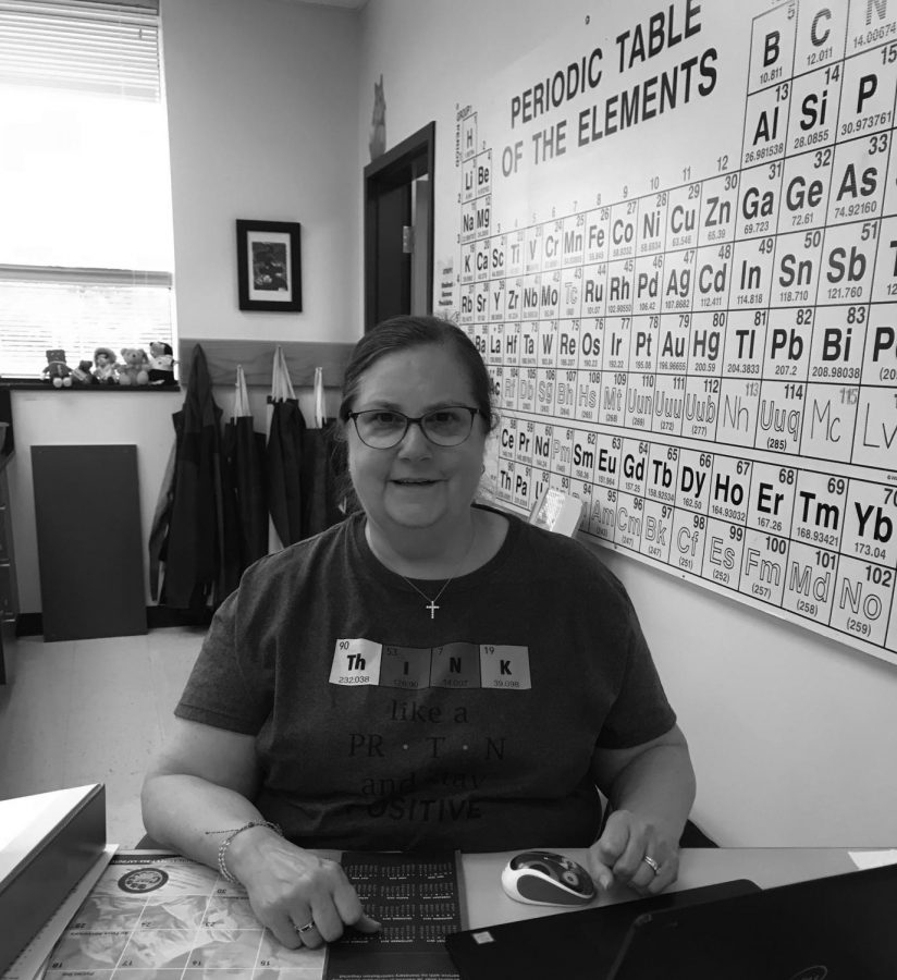 Hughes sits at her desk with a class full of students, offering them help with chemistry assignments in Learning Seminar.