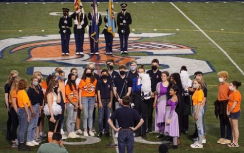 The choir sings the national anthem at the Homecoming football game, showcasing their skills on the field as they performed.