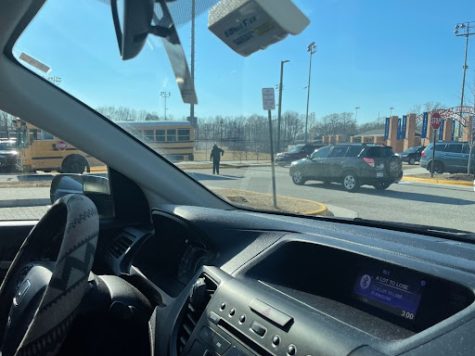 Buses and cars alike follow the hand gestures of faculty to exit the lot. Faculty recently coned-off a lane at the stop sign to mitigate various paths of entry causing “right-of-way” headaches.