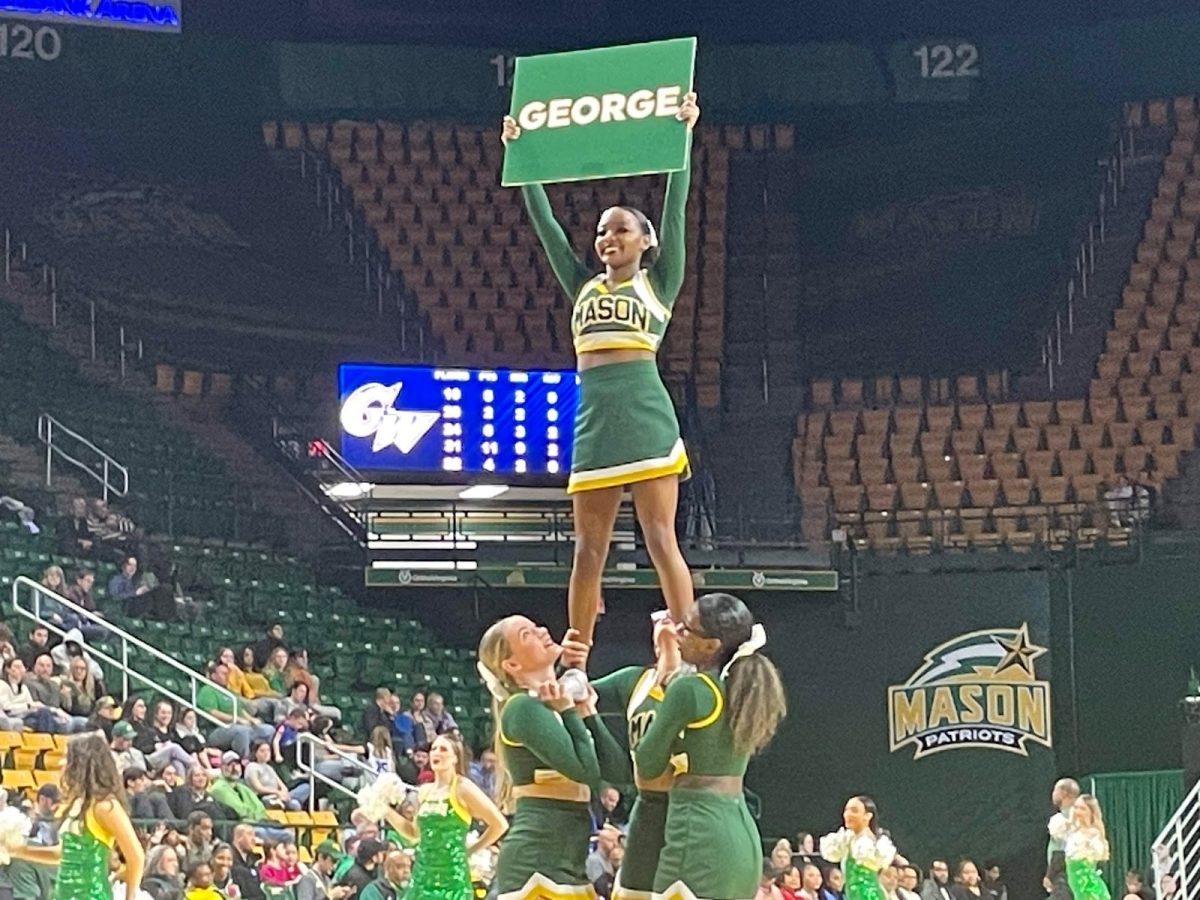 George Mason University cheerleaders lead the crowd in a “George!” chant. Other spirited traditions at the game included an alumni camera, spotting George Mason alumni throughout the crowd.