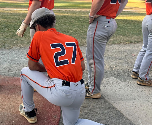 Freshman Gavin Price, in a solemn moment before stepping on the field, bows his head in silent prayer. Here, he finds a pocket of peace, grounding himself in a personal tradition that speaks to the heart of his dedication and spirit.